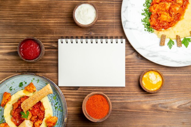 Vista superior de sabrosas rodajas de pollo con puré de patatas en mesa de madera marrón