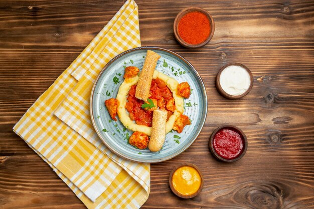 Vista superior de sabrosas rodajas de pollo con puré de patatas en mesa marrón