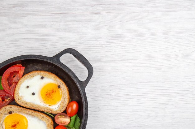 Vista superior sabrosas tostadas de huevo con tomates dentro de la sartén sobre fondo blanco desayuno almuerzo ensalada comida comida color libre lugar