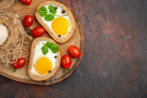 Vista superior sabrosas tostadas de huevo con tomates sobre fondo marrón oscuro desayuno almuerzo foto en color ensalada de la mañana