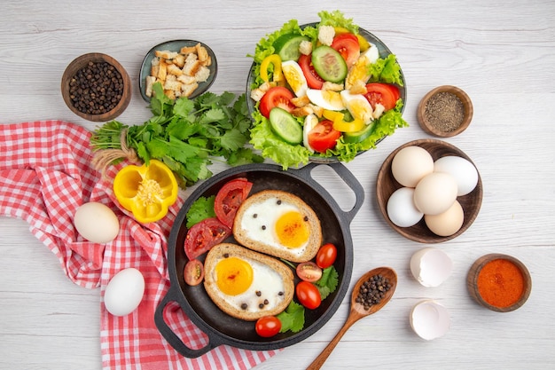 Vista superior sabrosas tostadas de huevo con verduras y ensalada sobre fondo blanco desayuno almuerzo comida color comida foto ensalada de la mañana
