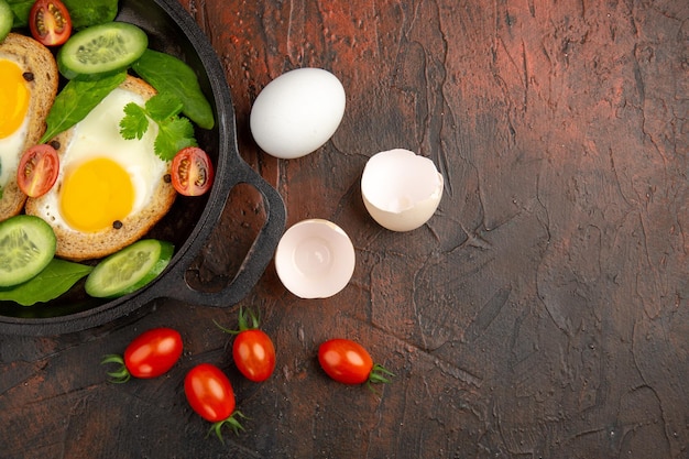 Vista superior sabrosas tostadas de huevo con verduras en rodajas dentro de la sartén sobre fondo oscuro comida huevo comida almuerzo freír foto en color tostadora
