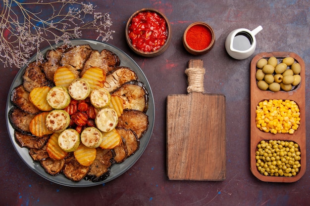 Vista superior sabrosas verduras al horno patatas y berenjenas en el horno de comida de escritorio oscuro cocinar verduras hornear