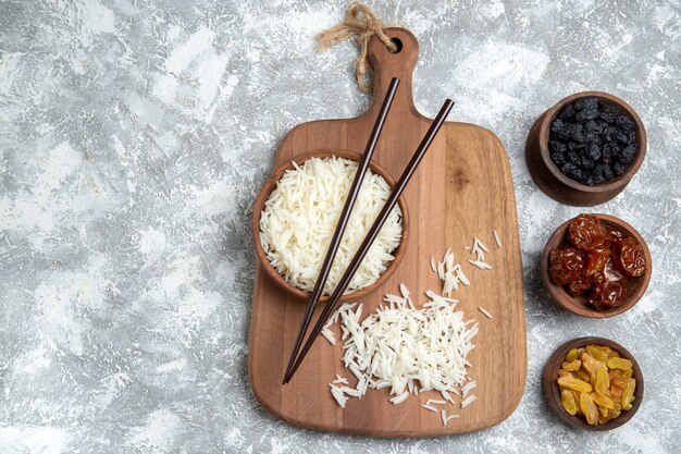 Vista superior sabroso arroz cocido dentro de un plato marrón con pasas en blanco