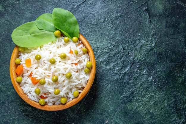 Vista superior del sabroso arroz hervido con judías verdes dentro de un plato pequeño en el escritorio oscuro