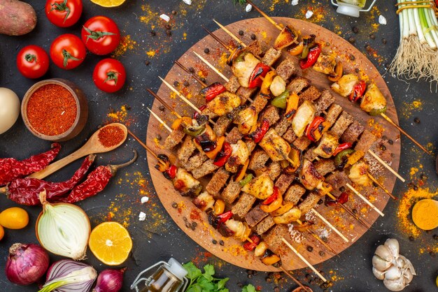 Vista superior del sabroso kebab de pollo en la tabla de servir de madera y otras cosas en la mesa