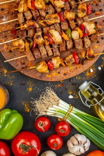 Vista superior del sabroso kebab de pollo en tablero de madera en la mesa oscura