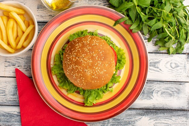 Vista superior del sabroso sándwich de pollo con ensalada verde y verduras papas fritas en rústica superficie gris