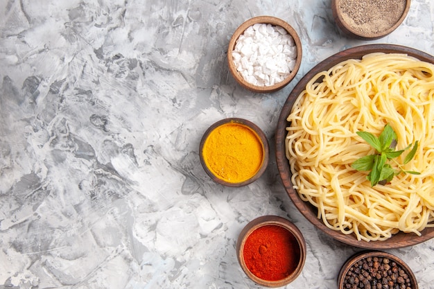 Vista superior de sabrosos espaguetis con condimentos en una comida de pasta de masa blanca