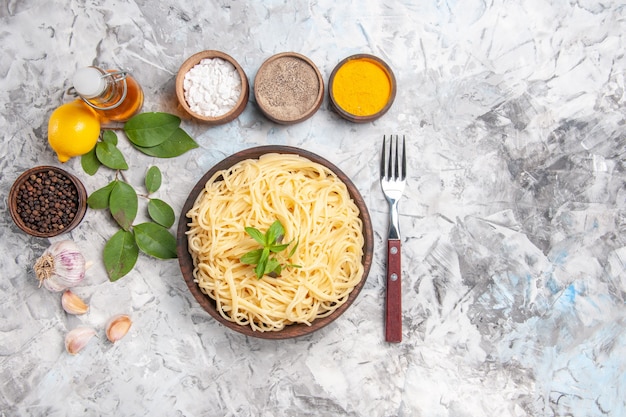 Vista superior de sabrosos espaguetis con condimentos en la comida de pasta de plato de masa blanca