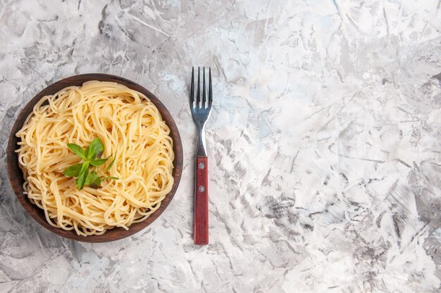 Vista superior de sabrosos espaguetis con hoja verde en pasta de plato de comida de masa blanca