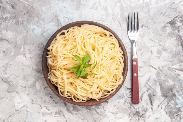 Vista superior de sabrosos espaguetis con hoja verde en pasta de plato de comida de masa blanca