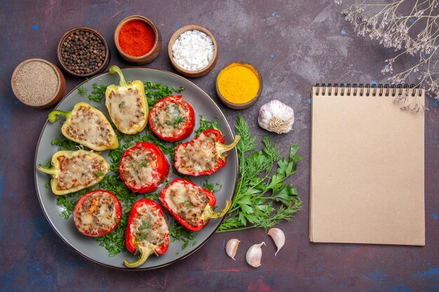 Vista superior sabrosos pimientos deliciosa comida cocinada con verduras de carne y condimentos en la superficie oscura plato cena comida comida