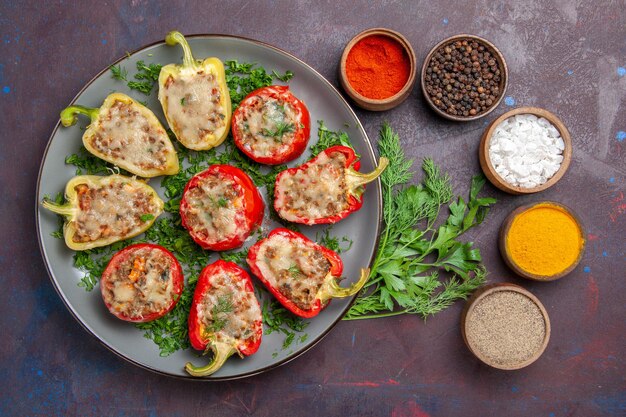 Vista superior sabrosos pimientos deliciosa comida cocinada con verduras de carne y condimentos en la superficie oscura plato cena comida comida