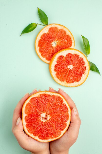 Vista superior de sabrosos pomelos en rodajas jugosas en la superficie azul claro