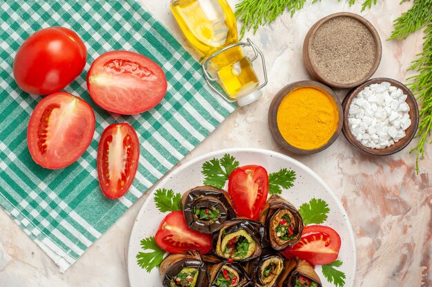 Vista superior de sabrosos rollos de berenjena con condimentos tomates y verduras