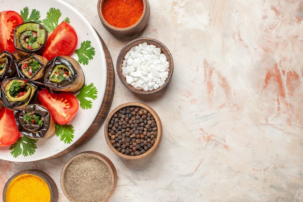 Vista superior de sabrosos rollos de berenjena con tomates y diferentes condimentos