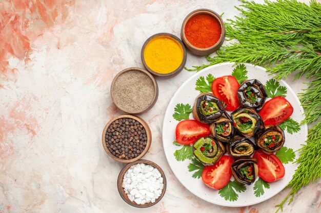 Vista superior de sabrosos rollos de berenjena con tomates verdes y condimentos