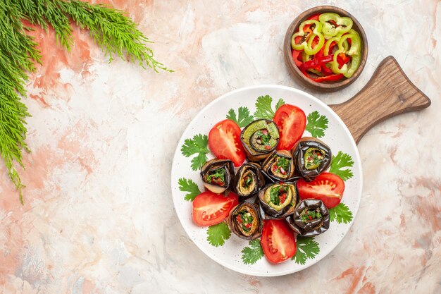 Vista superior de sabrosos rollos de berenjena con tomates y verduras