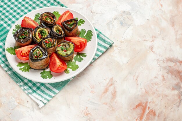 Vista superior de sabrosos rollos de berenjena con tomates y verduras