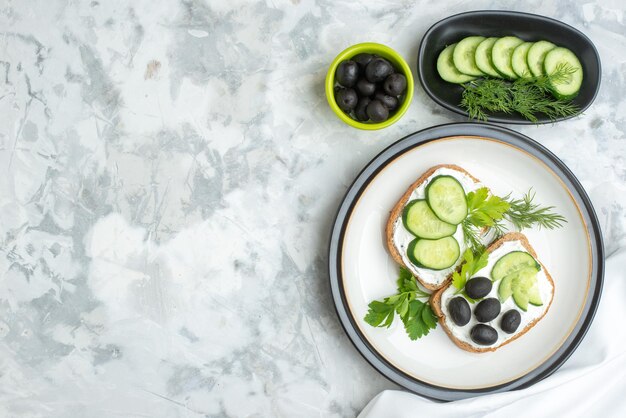 Vista superior sabrosos sándwiches con aceitunas y pepinos dentro del plato fondo blanco salud tostadas comida hamburguesa comida pan almuerzo horizontal