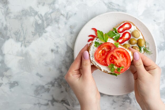 Vista superior sabrosos sándwiches con tomates y aceitunas dentro del plato sobre fondo blanco comida comida saludable almuerzo tostada horizontal hamburguesa