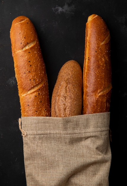 Foto gratuita vista superior del saco lleno de panes baguette sobre fondo negro