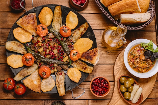 Vista superior de saj azerbaiyano cizbiz cocinado con berenjena patata tomate y pimiento en sartén de hierro fundido