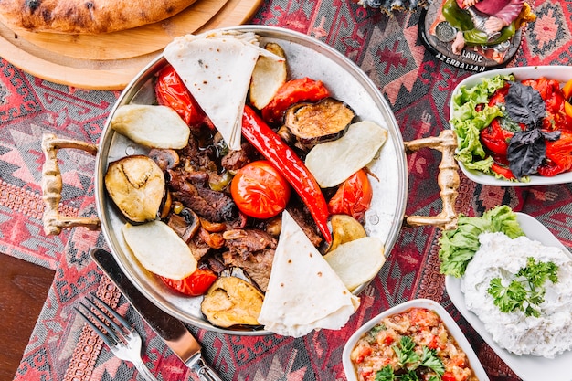 Vista superior de salvia de carne con pan de pita tomates y ensaladas sobre la mesa