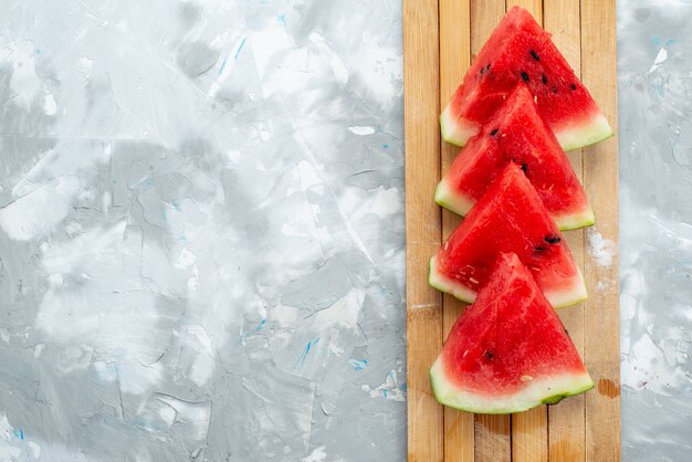 Una vista superior de sandía fresca en rodajas dulce y suave en madera marrón y blanca, color de verano de frutas