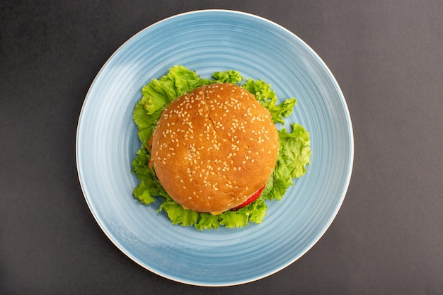 Vista superior del sándwich de pollo con ensalada verde y verduras dentro de la placa sobre la superficie oscura