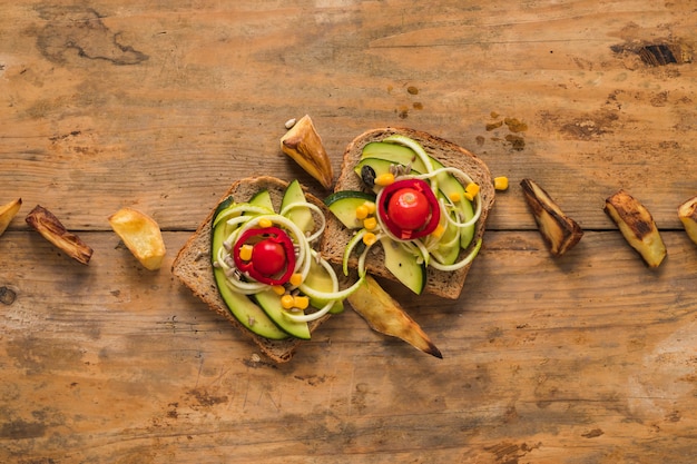 Foto gratuita vista superior de sandwich de verduras con una rodaja de patata asada en mesa de madera