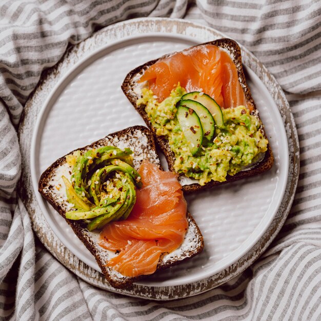 Vista superior de sándwiches de desayuno en la cama con salmón y aguacate