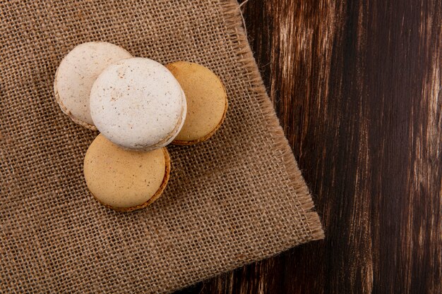 Vista superior de sándwiches de galleta sobre tela de saco y fondo de madera con espacio de copia