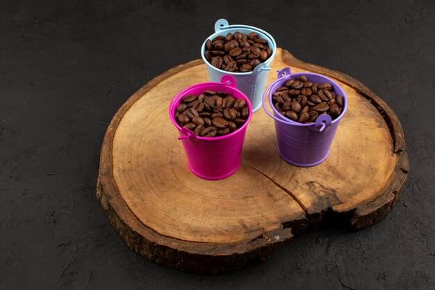 Vista superior de semillas de café café dentro de macetas multicolores en el piso oscuro