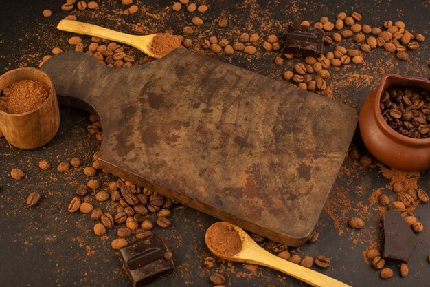 Una vista superior de semillas de café marrón con barras de choco por toda la mesa marrón