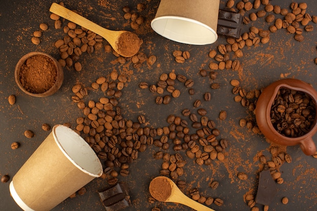 Una vista superior de semillas de café marrón con barras de chocolate y tazas de café