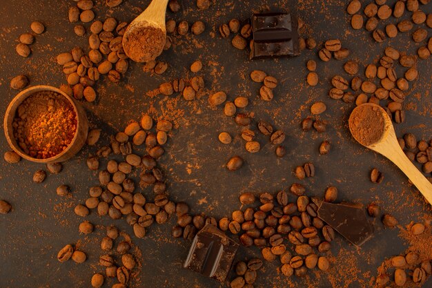 Una vista superior de semillas de café marrón con barras de chocolate en todo el gránulo de grano de semilla de café de fondo marrón