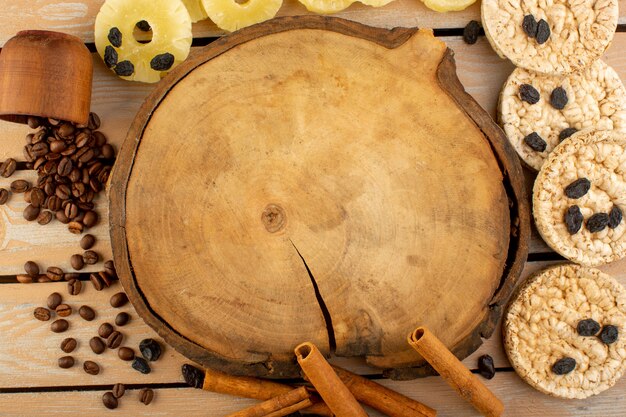 Una vista superior de las semillas de café marrón con galletas de canela y piña seca en la mesa rústica crema de grano de semillas de café de galletas