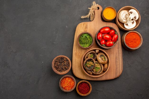 Vista superior de setas cocidas con condimentos en mesa oscura seta comida salvaje madura