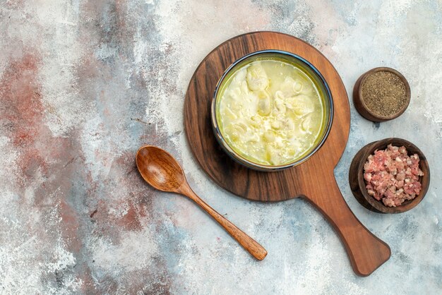 Vista superior sopa de albóndigas dushbara en tazones de fuente de tabla de cortar con cuchara de madera de carne y pimienta en lugar libre de superficie desnuda