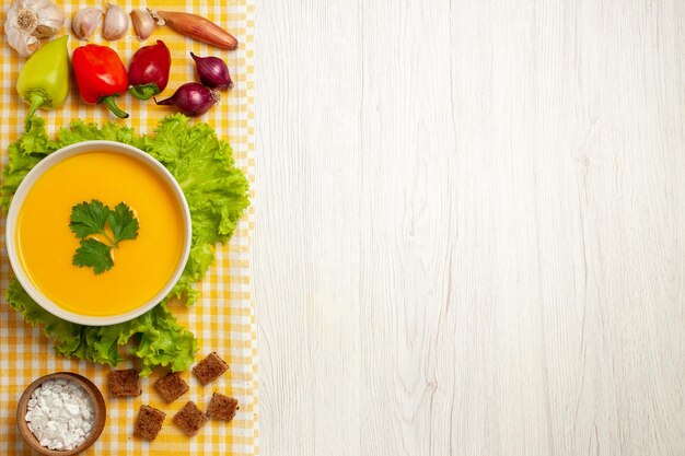 Vista superior de la sopa de calabaza con verduras en blanco