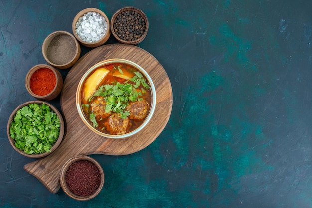 Vista superior de la sopa de carne con albóndigas verdes y patatas en rodajas en el escritorio azul oscuro