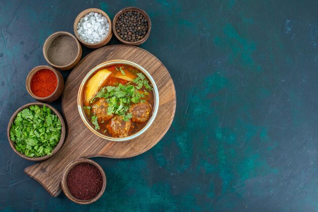 Vista superior de la sopa de carne con albóndigas verdes y patatas en rodajas en el escritorio azul oscuro