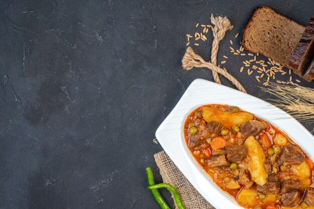 Vista superior de la sopa de carne con guarnición de pan negro pimientos verdes en el espacio de copia de la mesa