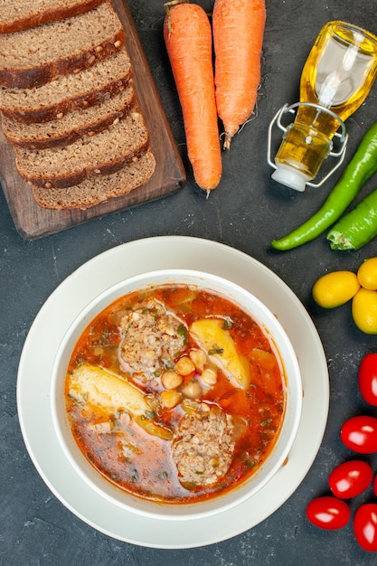 Foto gratuita vista superior de sopa de carne con hogazas de pan y condimentos sobre fondo gris oscuro