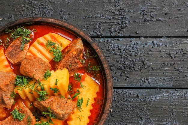 Vista superior de la sopa de carne con patatas y verduras en la salsa de comida de plato de carne de escritorio oscuro