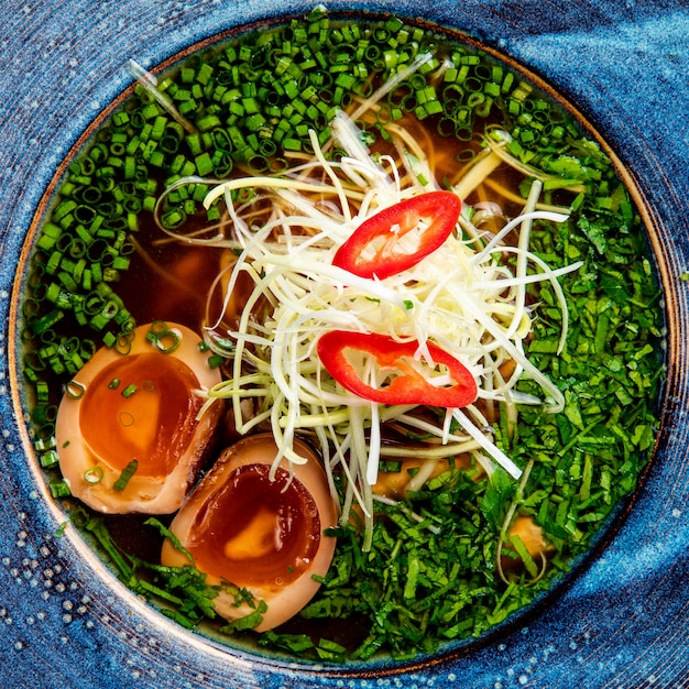 Vista superior de la sopa de fideos aisan con huevos picados cebolla verde y repollo en un plato