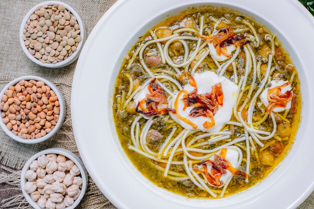 Vista superior sopa de frijoles con fideos de cebolla a la parrilla, crema agria y frijoles