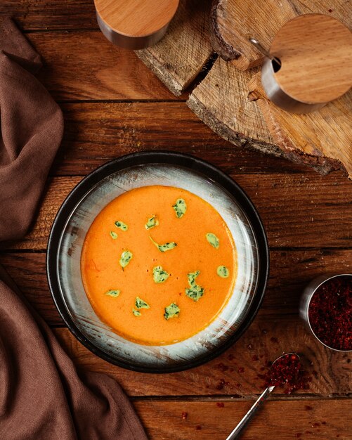 Una vista superior de sopa de naranja con hojas en el escritorio de madera comida comida